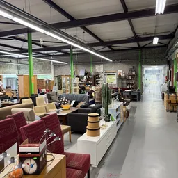 Winkelvloer met diverse meubels, stoelen en huisraad uitgestald onder industrieel plafond
