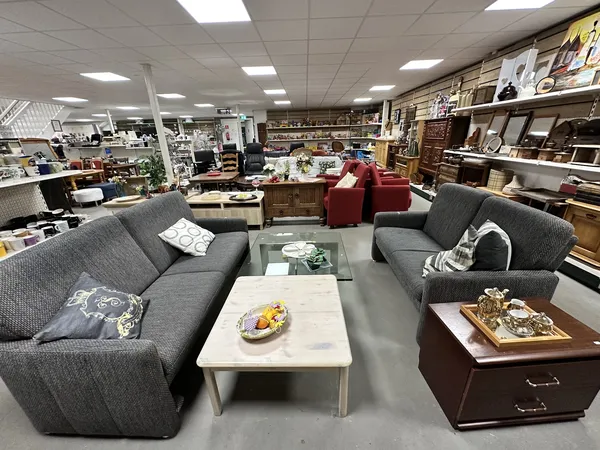 Winkelvloer met grijze en rode zitmeubels, salontafels en houten kasten met diverse gebruiksvoorwerpen