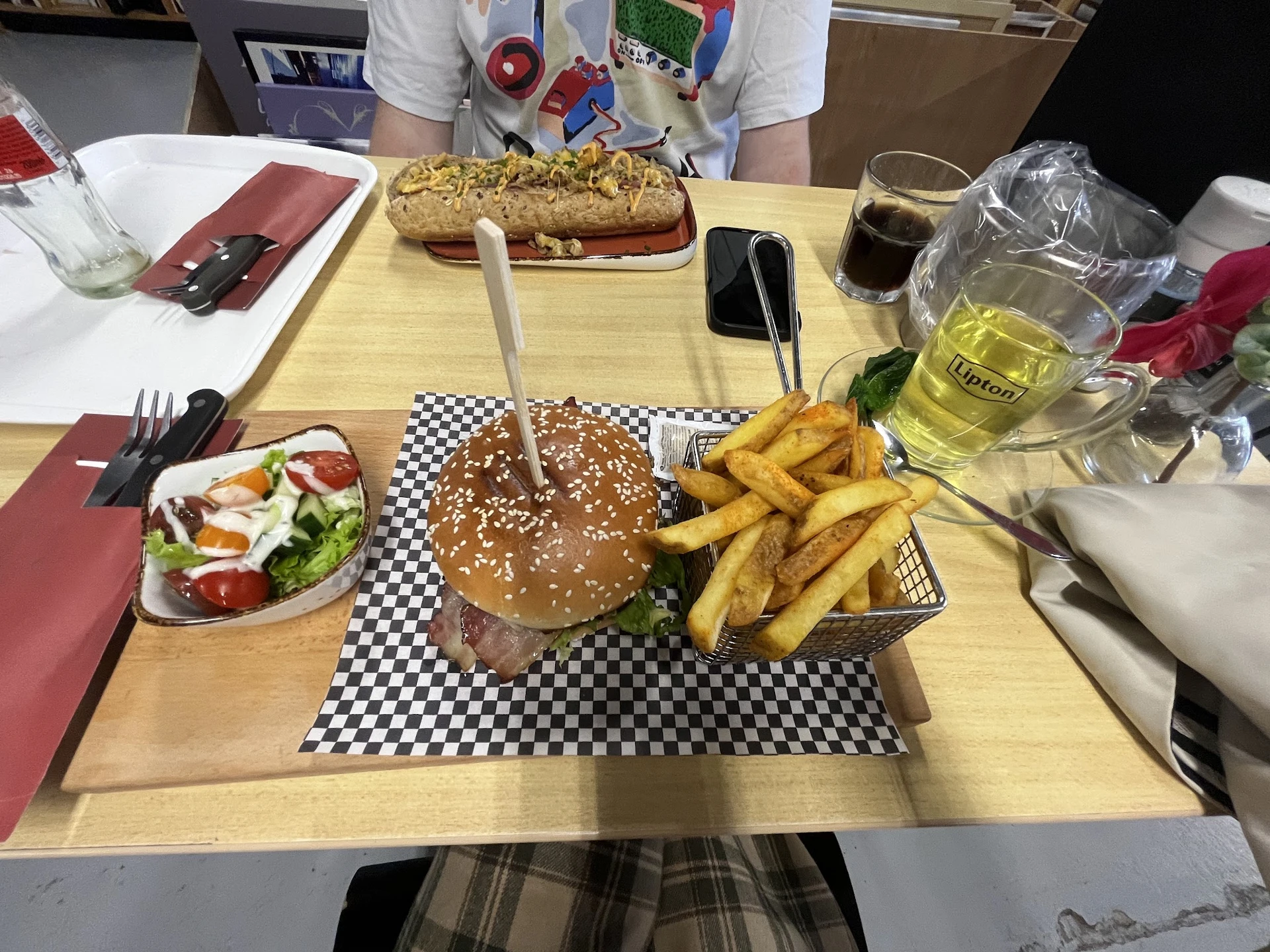 Maaltijd met hamburger, friet, salade en dranken op tafel in lunchroom