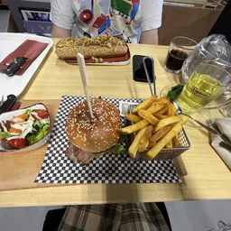 Maaltijd met hamburger, friet, salade en dranken op tafel in lunchroom