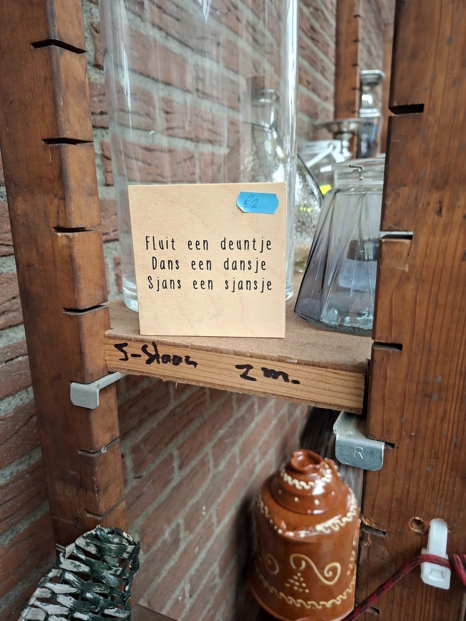 Houten deurtje met gedicht op papier geplakt, handgeschreven aantekening onderaan