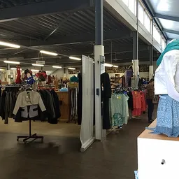 Winkelvloer met kledingrekken, toonpoppen en uitgestalde tweedehands kleding in een kringloopwinkel