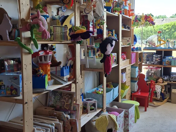 Winkelinterieur met houten stellingen vol speelgoed, boeken, huishoudartikelen en diverse tweedehands spullen