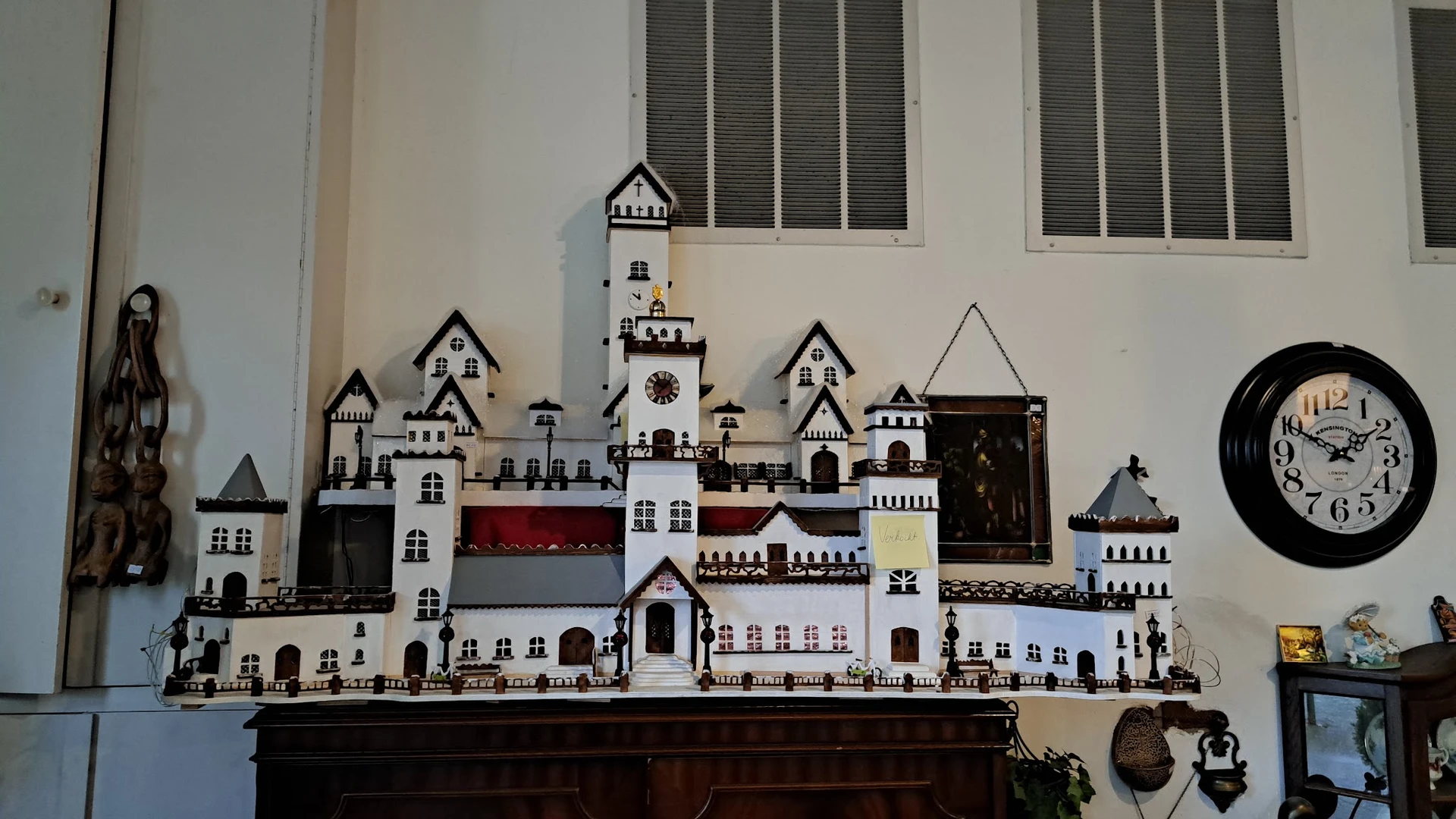 Uitgebreide miniatuurburchtverzameling met witte en rode torens en gebouwen op een donkere kast