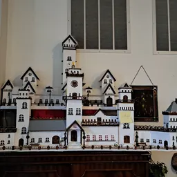 Uitgebreide miniatuurburchtverzameling met witte en rode torens en gebouwen op een donkere kast