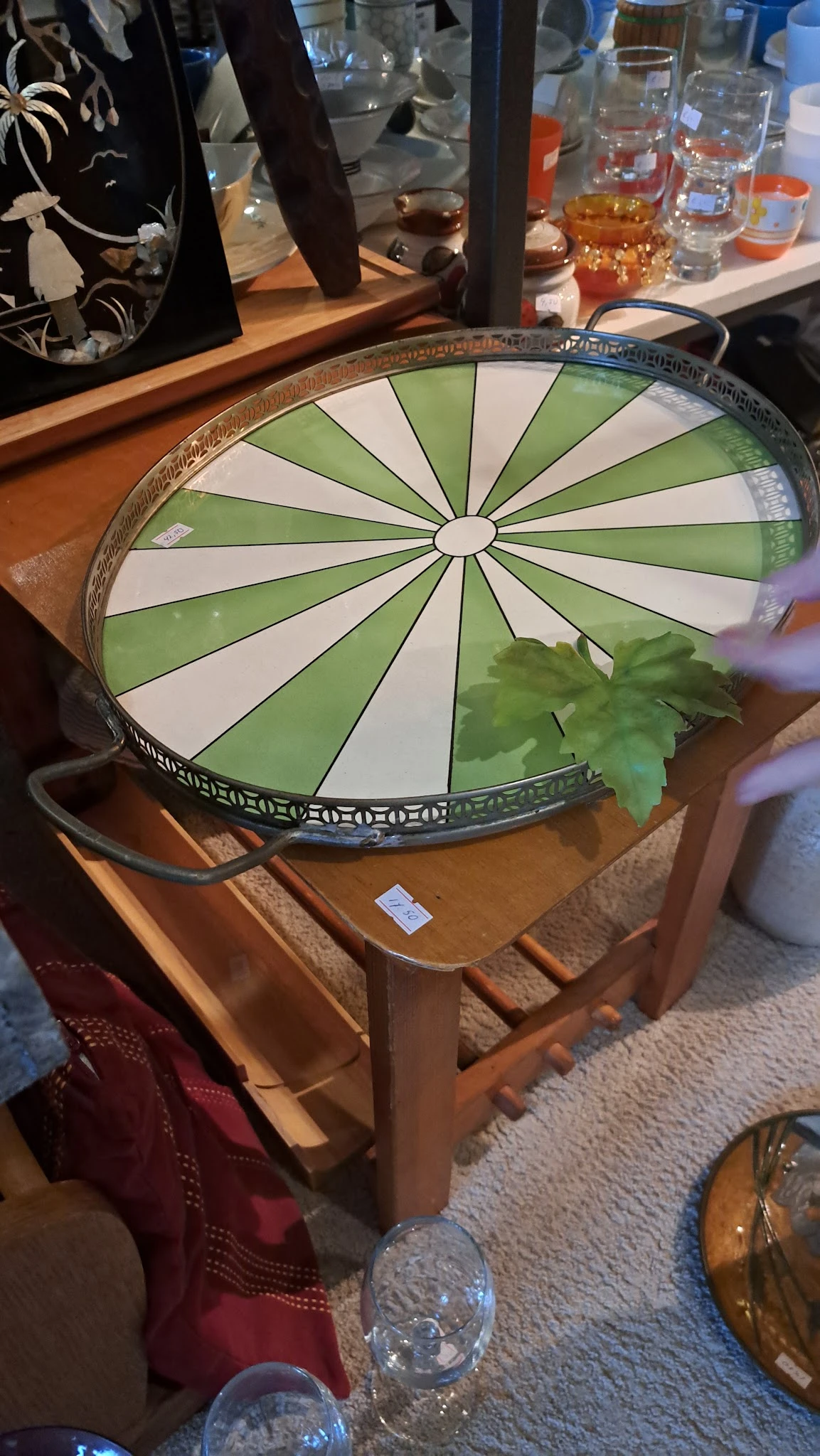 Groen-witte decoratieve plafondlamp op houten tafel in een kringloopwinkel