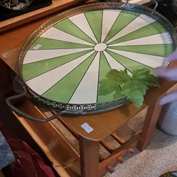 Groen-witte decoratieve plafondlamp op houten tafel in een kringloopwinkel