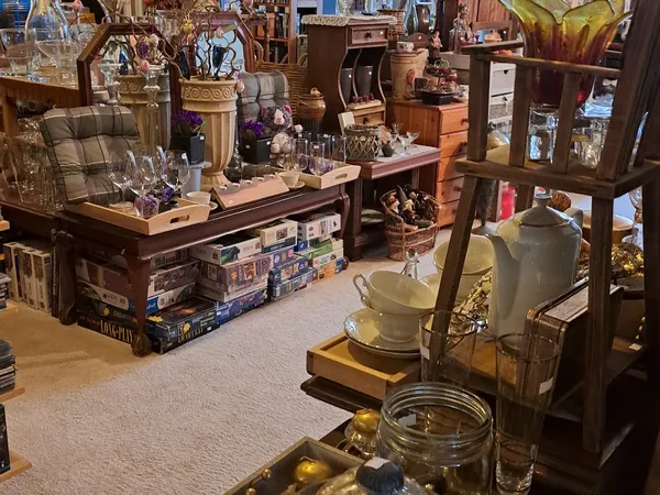 Winkelvloer met houten display-tafels vol decoratieartikelen, glazen voorwerpen, vazen en diversen knuisterij