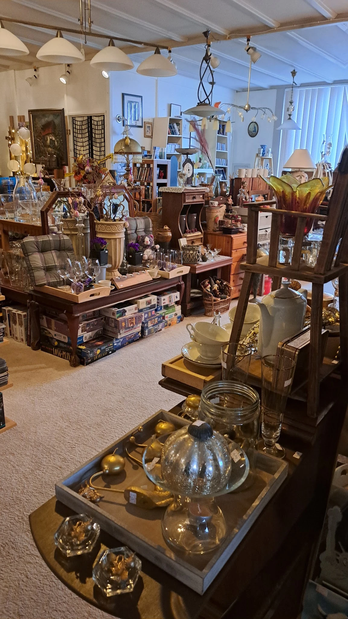 Winkelvloer met houten display-tafels vol decoratieartikelen, glazen voorwerpen, vazen en diversen knuisterij