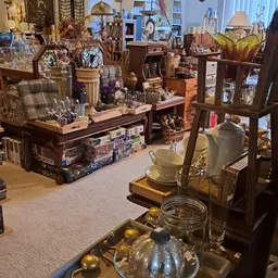 Winkelvloer met houten display-tafels vol decoratieartikelen, glazen voorwerpen, vazen en diversen knuisterij