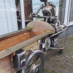 Tweedehands fietsen met zijspannen en houten aanhangwagen buiten de winkel