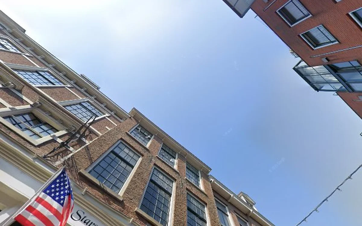 Voorgevel van bakstenen gebouw met ramen en Amerikaanse vlag, gezien van onderaf