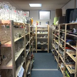 Winkelinterieur met houten stellingen vol uitgestalde spullen, gangen en overhead verlichting