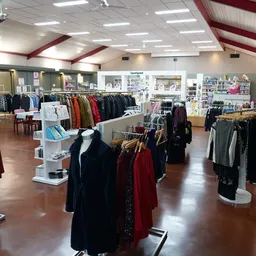 Winkelvloer van kringloopwinkel met rekken tweedehands kleding, verlichte plafonds en winkelafdelingen
