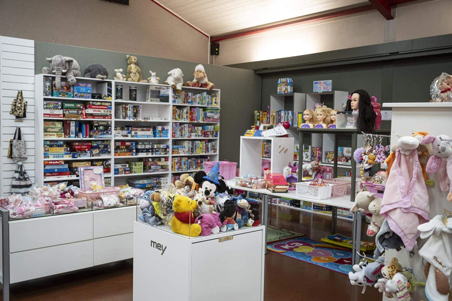 Uitgestalde collectie poppen, knuffels en speelgoed op witte stellingen enDisplayBox.
