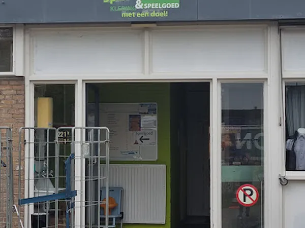 Winkelpui van kringloopwinkel met witte en groene deuren, ramen en uithangsignage