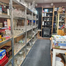 Gangpad in kringloopwinkel met glazen kasten vol servies en glaswerk aan beide zijden