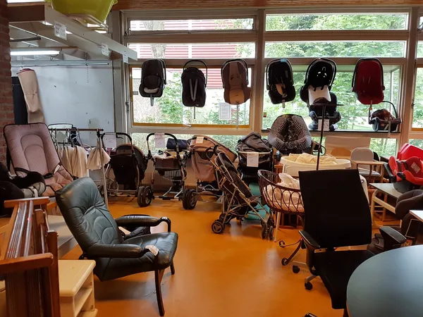 Winkelvloer met diverse kinderwagens, autostoelen en babyspullen uitgestald onder grote ramen