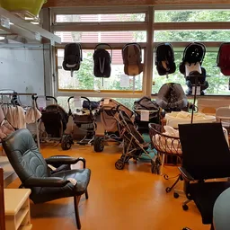 Winkelvloer met diverse kinderwagens, autostoelen en babyspullen uitgestald onder grote ramen