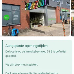 Gevel van kringloopwinkel met groene Tweede Kans-logo, ingang met planten en fietsenrek