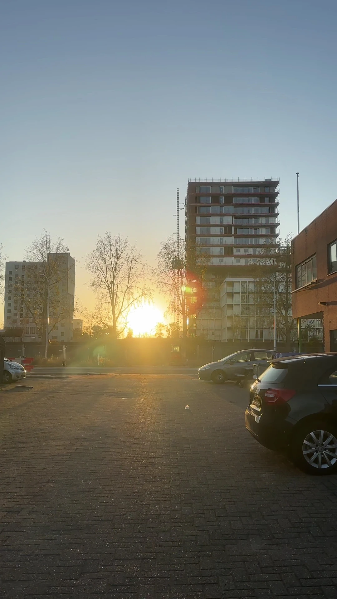 Parkeerplaats met auto's en appartementengebouwen bij zonsondergang