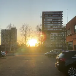Parkeerplaats met auto's en appartementengebouwen bij zonsondergang