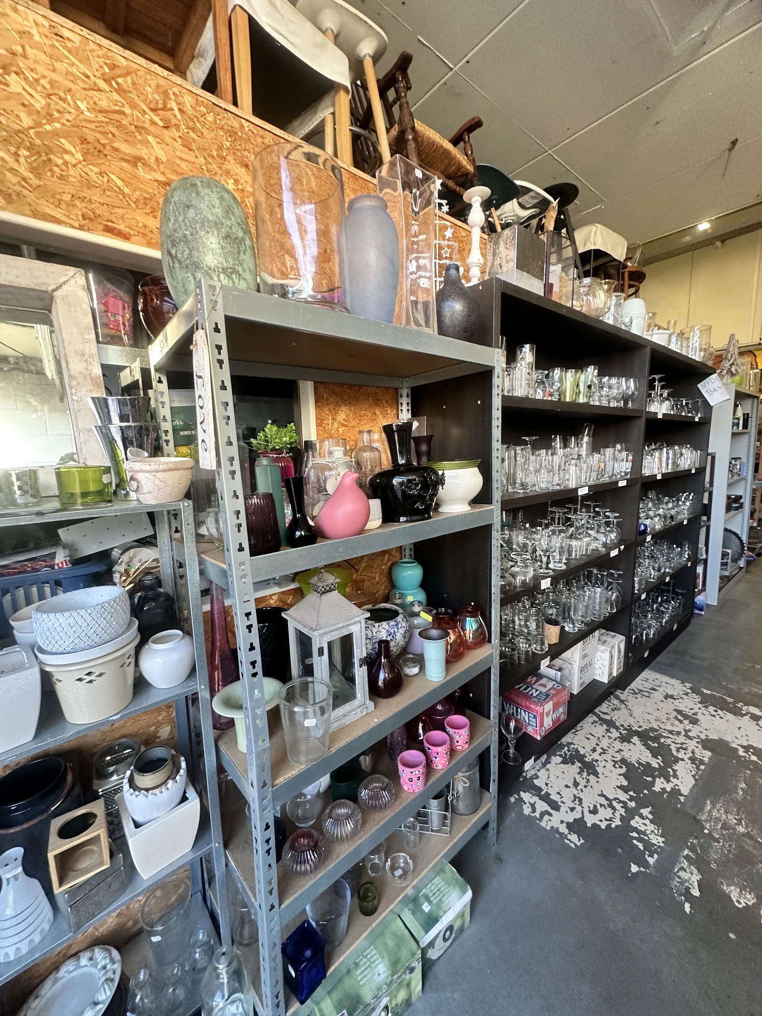 Metalen stellingen met diverse huishoudelijke artikelen, glazen, servies en decoratie-items