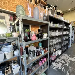 Metalen stellingen met diverse huishoudelijke artikelen, glazen, servies en decoratie-items