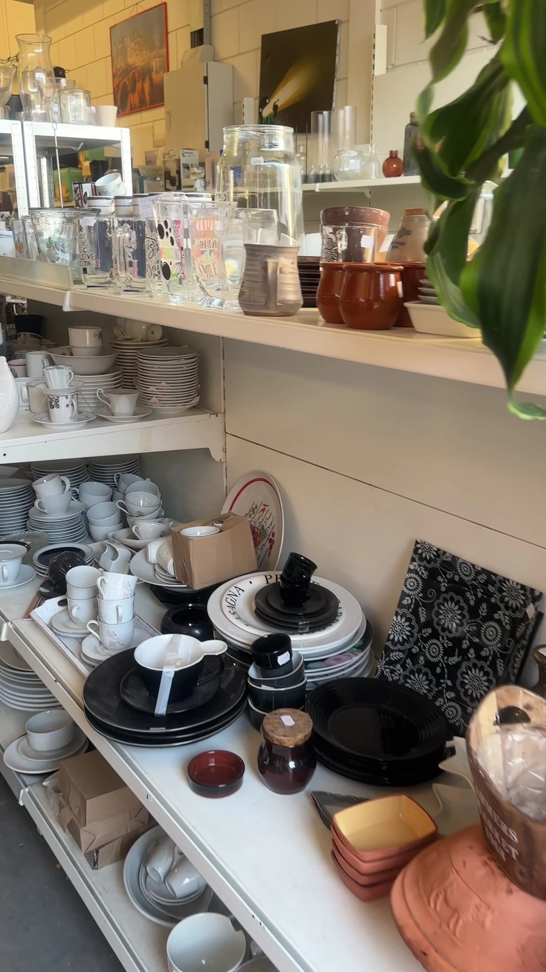 Kast met serviesgoed: stapels borden, kopjes, glazen en ander eetservies in wit en zwart