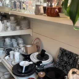 Kast met serviesgoed: stapels borden, kopjes, glazen en ander eetservies in wit en zwart