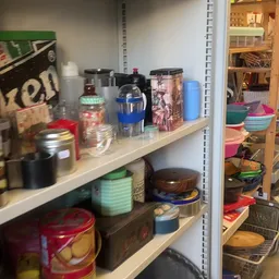 Stellingkast met diverse huishoudelijke artikelen zoals keukengerei, bewaardozen en keukenspullen