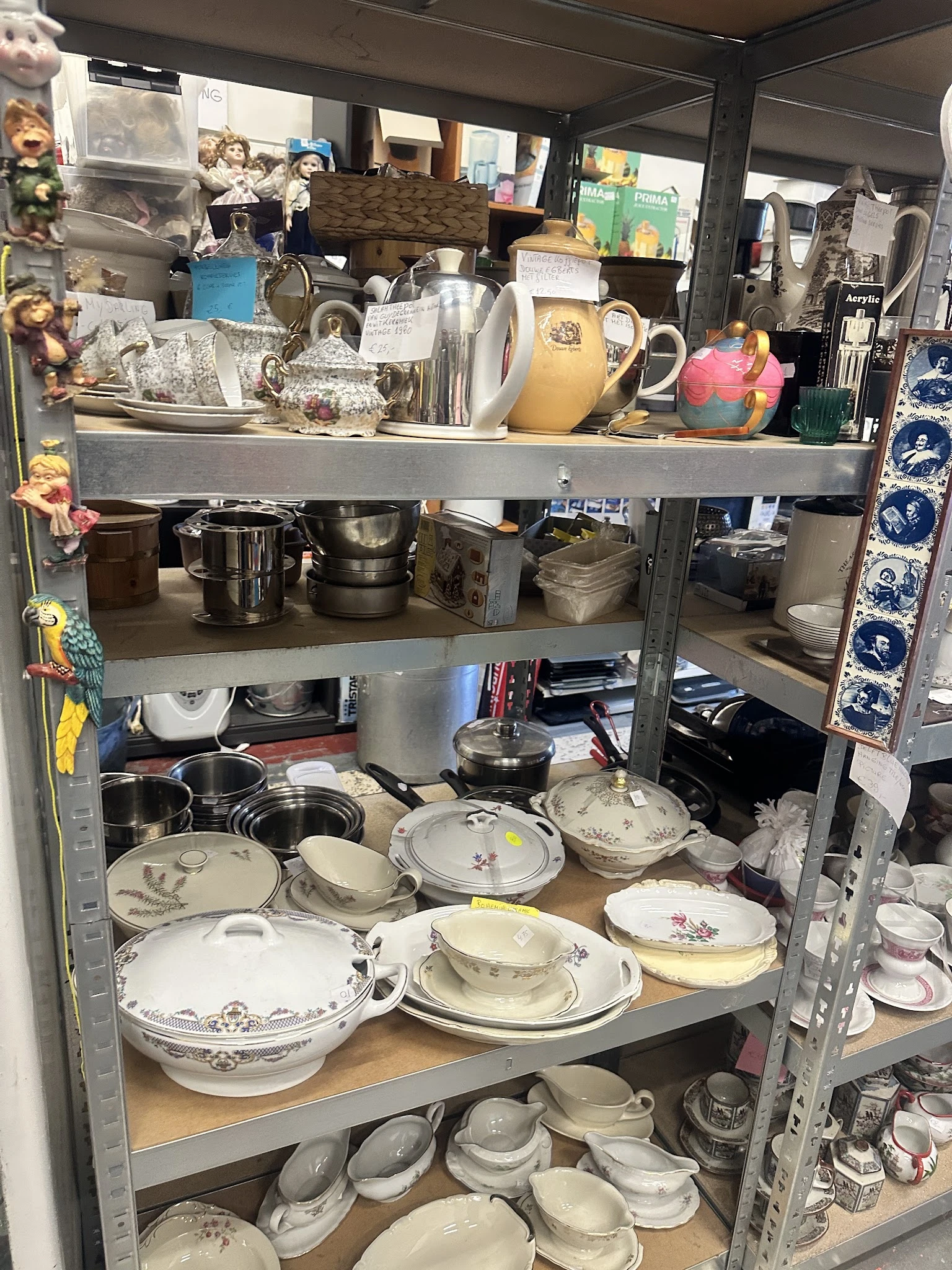 Metalen stellingkast met servies, porselein, schalen en andere huishoudartikelen op verschillende niveaus