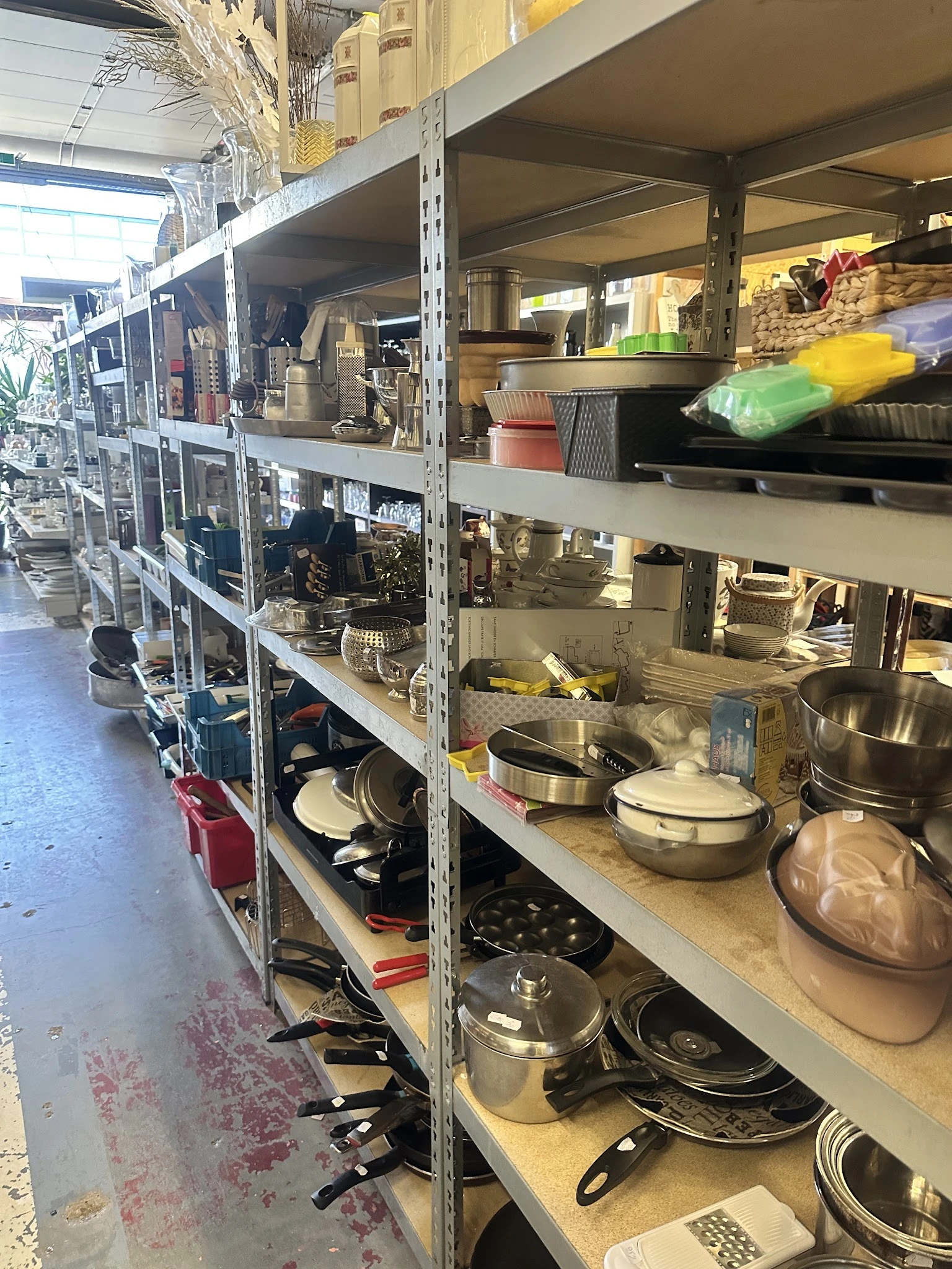 Stellingen met tweedehands keukengerei en pannen in de kringloopwinkel