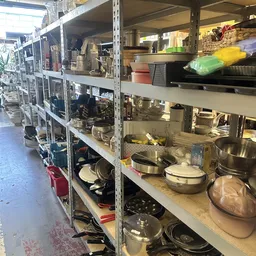 Stellingen met tweedehands keukengerei en pannen in de kringloopwinkel