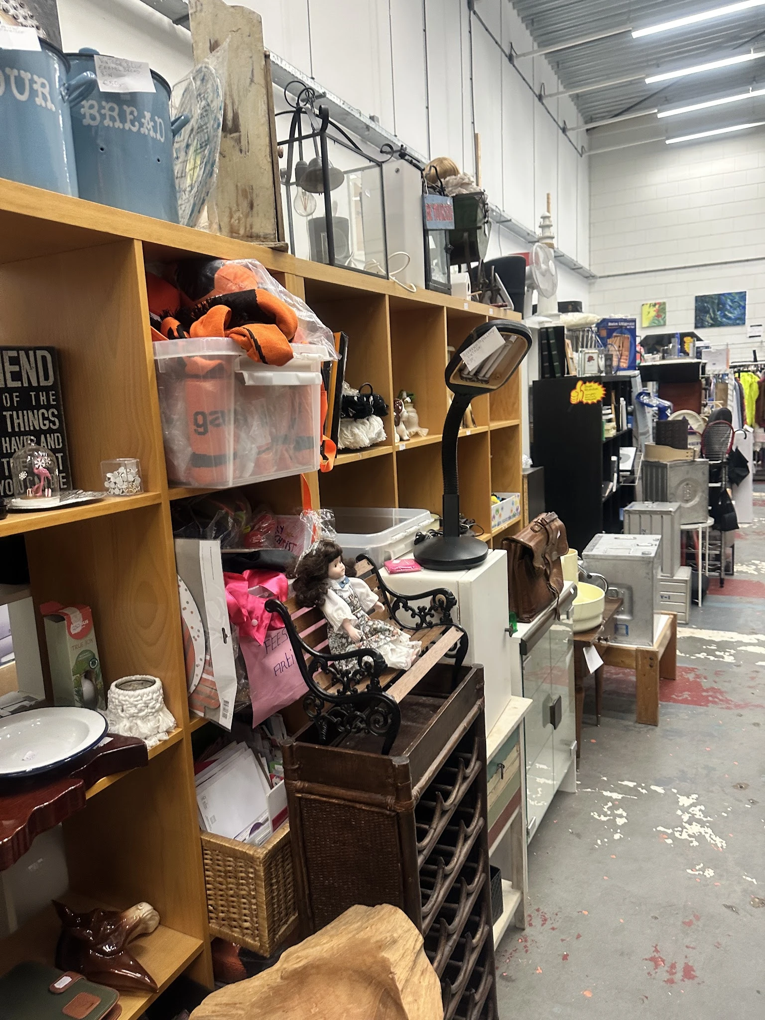 Winkelinterieur met houten stellingen vol tweedehands spullen, kleding en diverse items