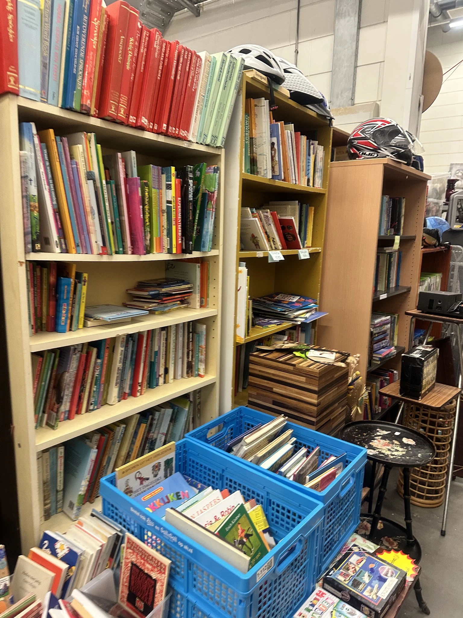 Boekenkasten met dvd's, cd's en boeken; blauwe krat met media op de vloer
