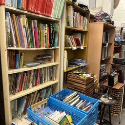 Boekenkasten met dvd's, cd's en boeken; blauwe krat met media op de vloer