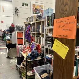 Boekenkasten met tweedehands boeken en prijs­kaarten met aanbiedingen, in een kringloopwinkel.