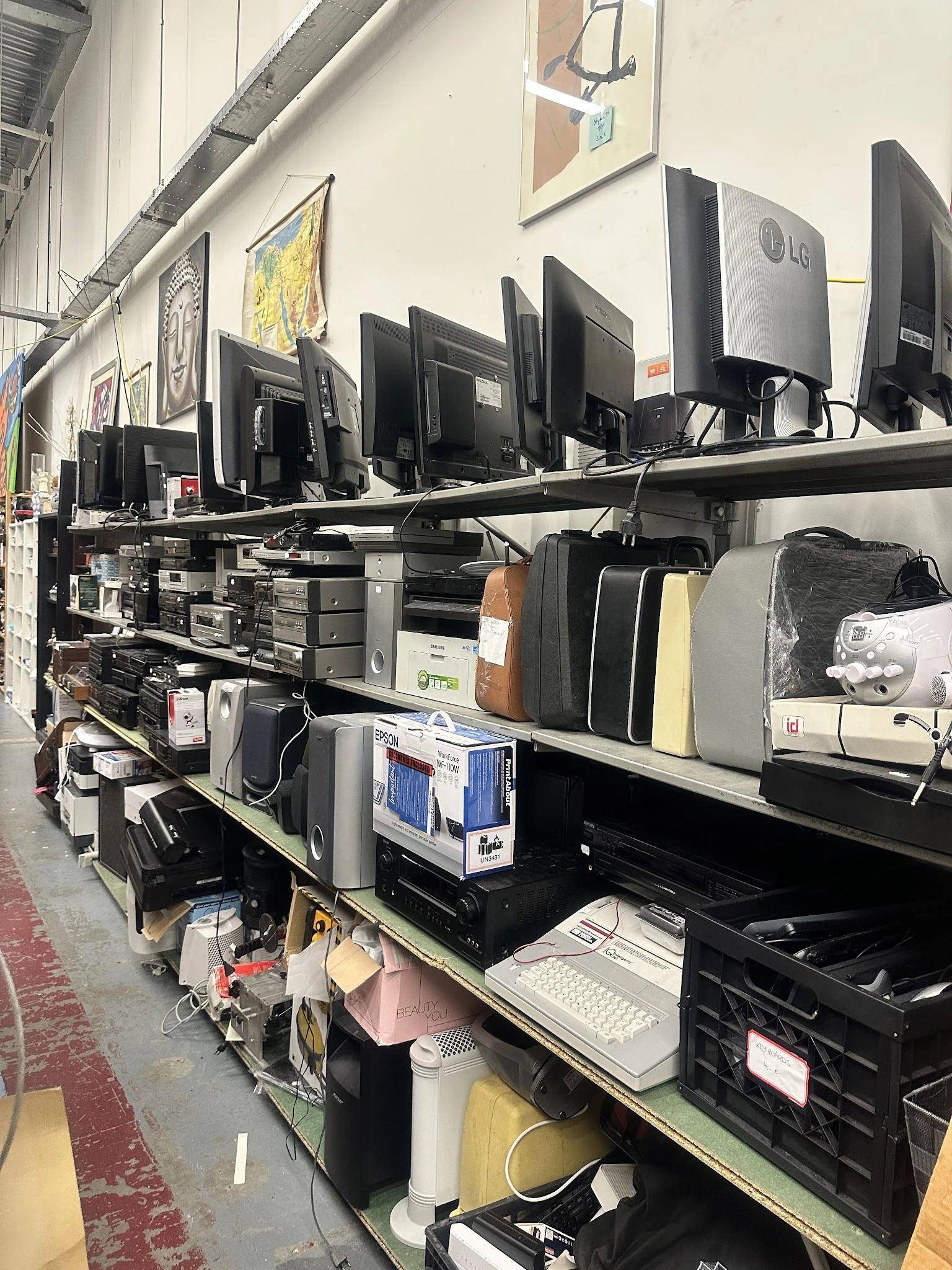 Rekken met elektronische apparatuur zoals monitoren, printers en computeronderdelen in een kringloopwinkel