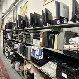 Rekken met elektronische apparatuur zoals monitoren, printers en computeronderdelen in een kringloopwinkel