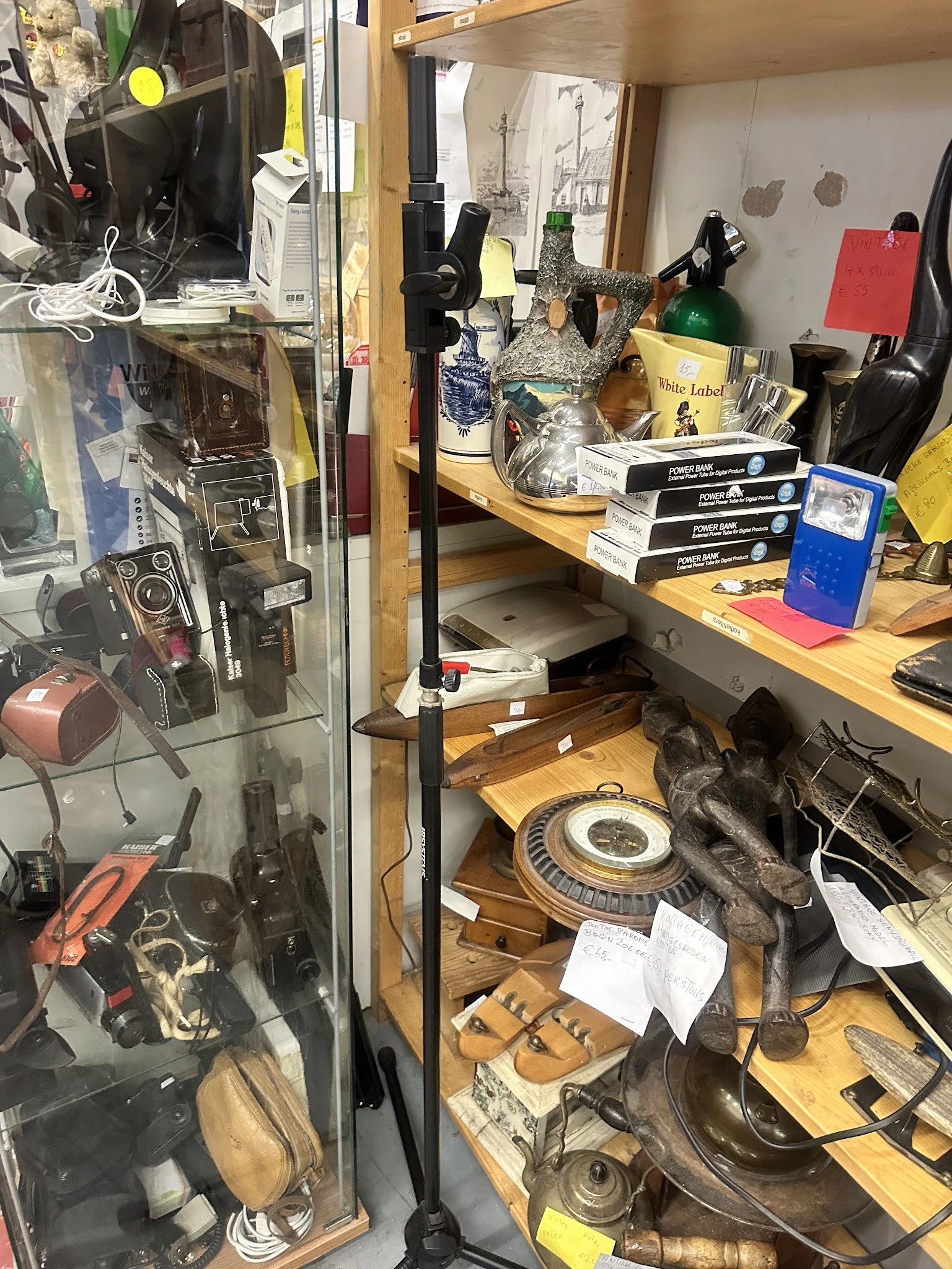 Werkplek met vintage camera's, boeken, flessen en diverse voorwerpen op houten tafels en in kasten.