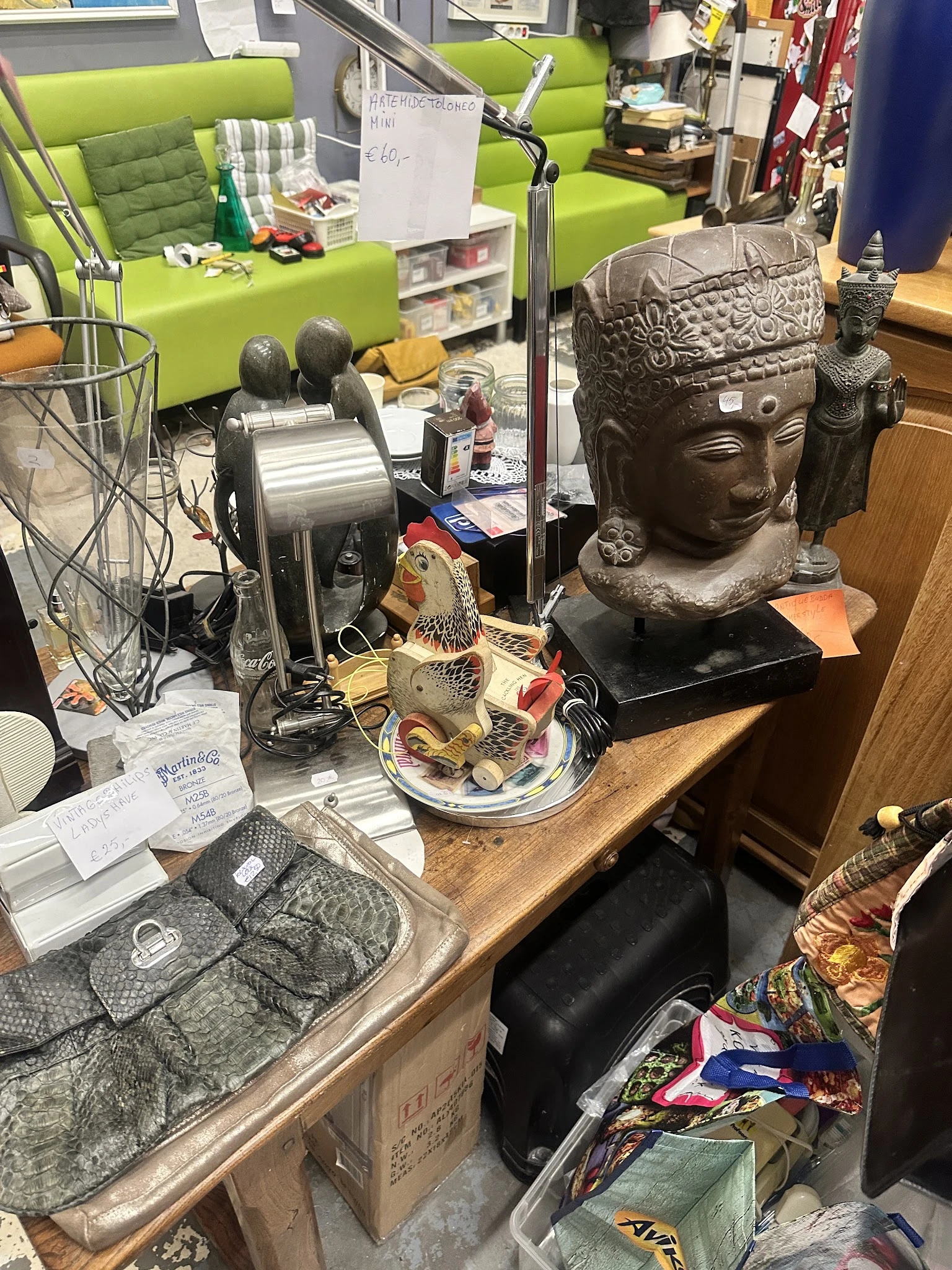 Tafelblad met decoratieve items: een Boeddha-hoofd, een gouden visje, ventilator en ander aardewerk