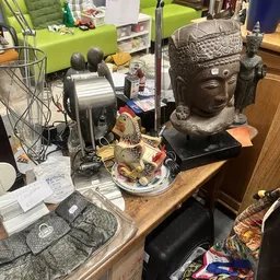 Tafelblad met decoratieve items: een Boeddha-hoofd, een gouden visje, ventilator en ander aardewerk