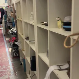 Witte stellingen met vakken en verschillende spullen in een kringloopwinkel