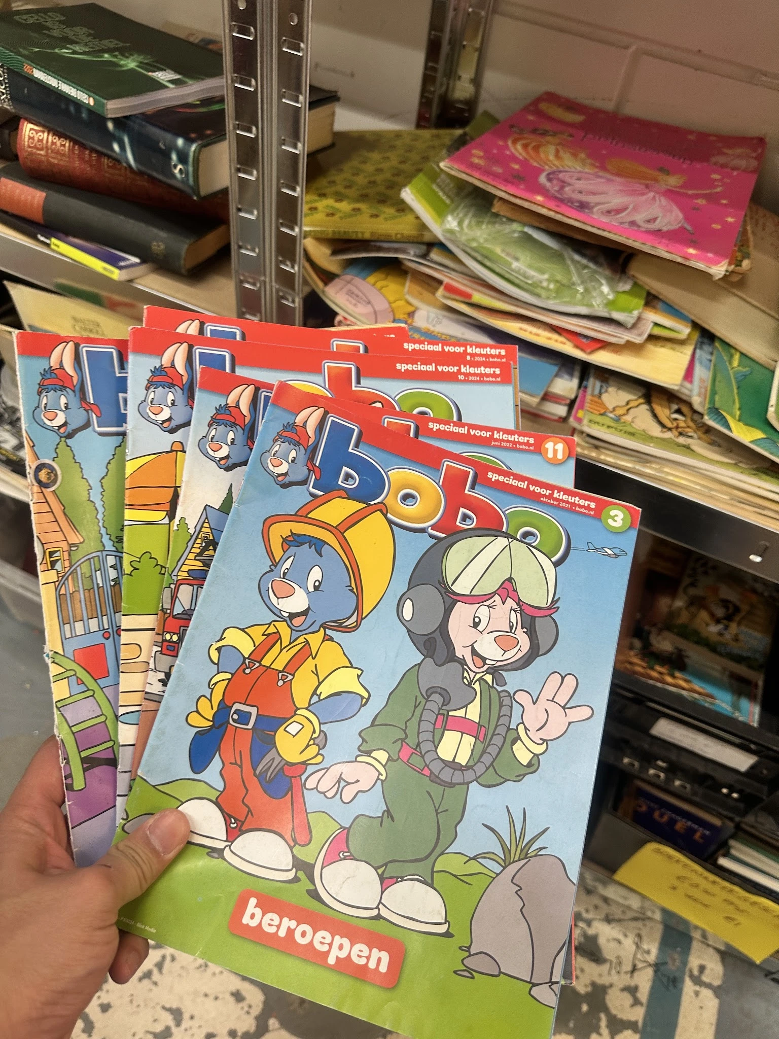 Stapel kinderboeken met cartoon-achtige illustraties in een kringloopwinkel