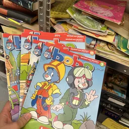 Stapel kinderboeken met cartoon-achtige illustraties in een kringloopwinkel