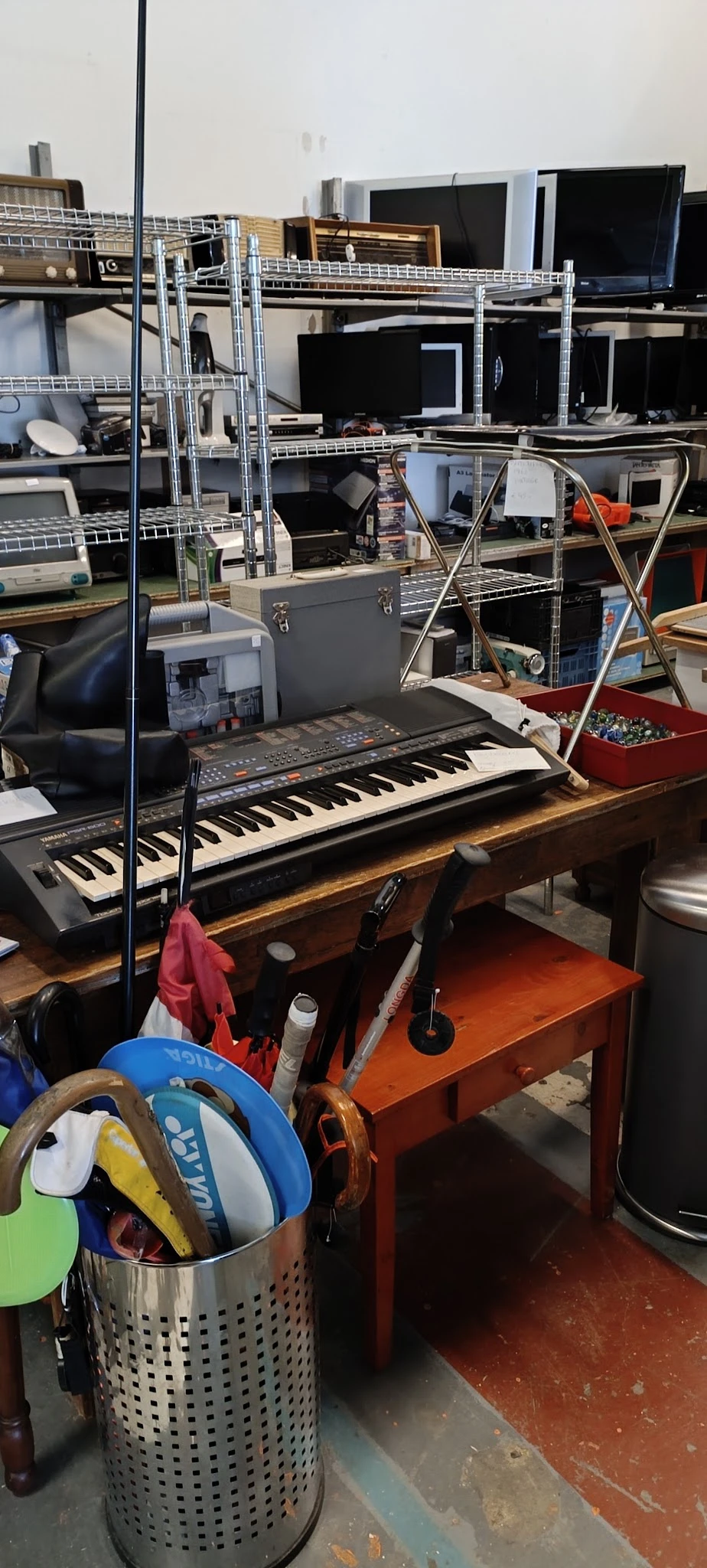 Elektronisch keyboard/synthesizer op houten tafel in werkruimte met muziekuitrusting op achtergrond
