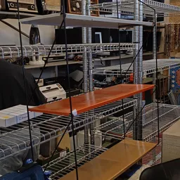 Metalen stellingen met houten werktafels en diverse kantoorapparatuur in de winkel