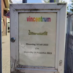 Wit bord met tekst over zomervakantie van Vincentrum, geplakt op een deur