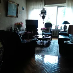 Zithoek met zwarte lederen fauteuils, salontafel en decoratieve objecten in een kringloopwinkel